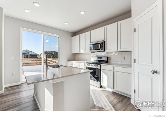 kitchen with white cabinets, a kitchen island with sink, stainless steel appliances, and sink