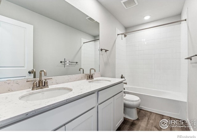 full bathroom with vanity, tiled shower / bath combo, hardwood / wood-style flooring, and toilet