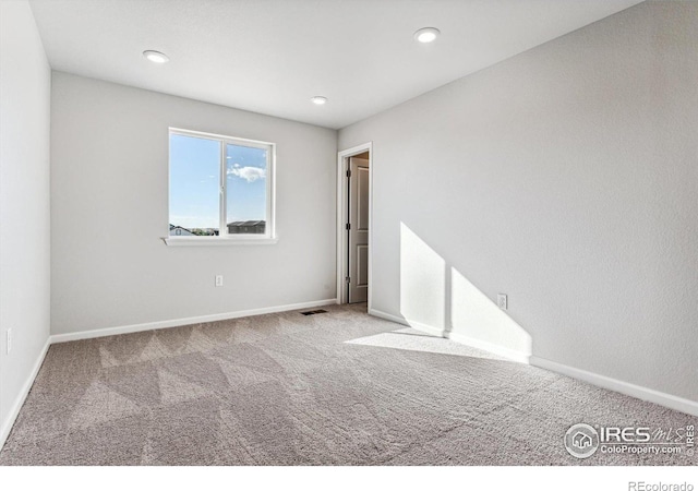 spare room with carpet floors, recessed lighting, baseboards, and visible vents