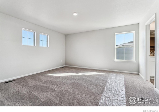 carpeted spare room featuring baseboards and visible vents
