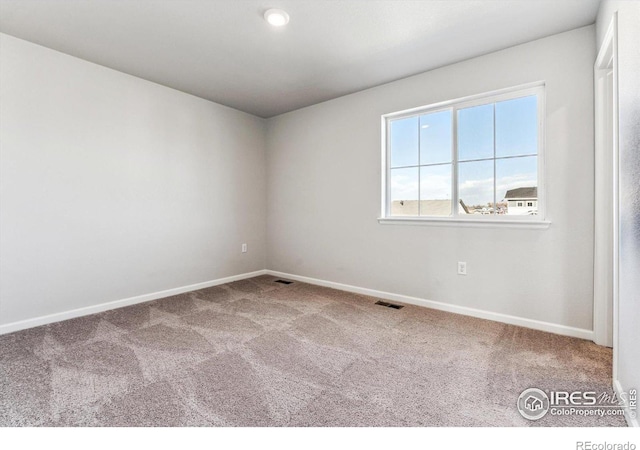 unfurnished room with carpet, visible vents, and baseboards