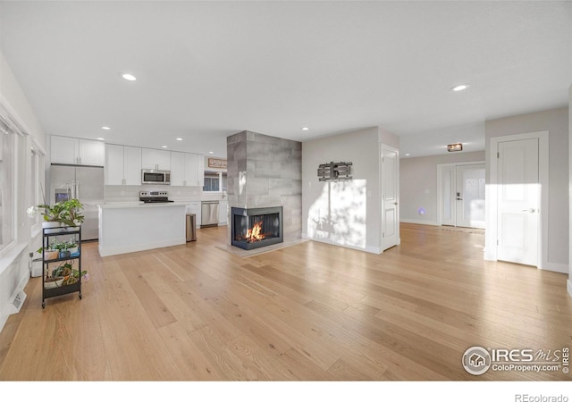 living room with light hardwood / wood-style flooring and a tiled fireplace