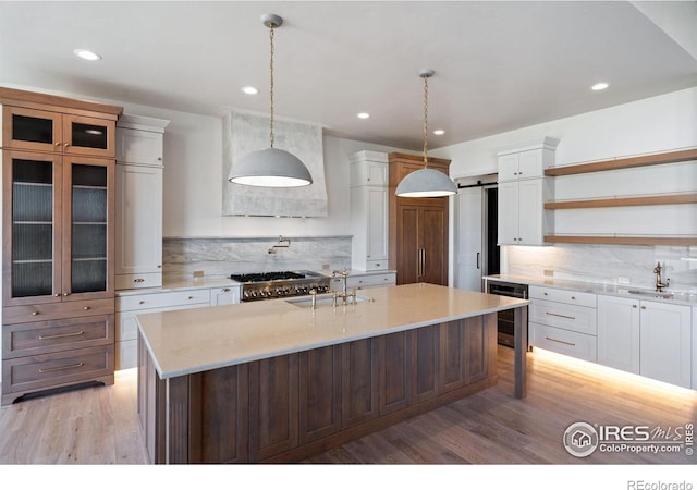 kitchen featuring hanging light fixtures, wine cooler, a barn door, light hardwood / wood-style floors, and white cabinets