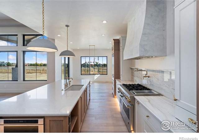 kitchen featuring high end stove, white cabinetry, sink, and a spacious island