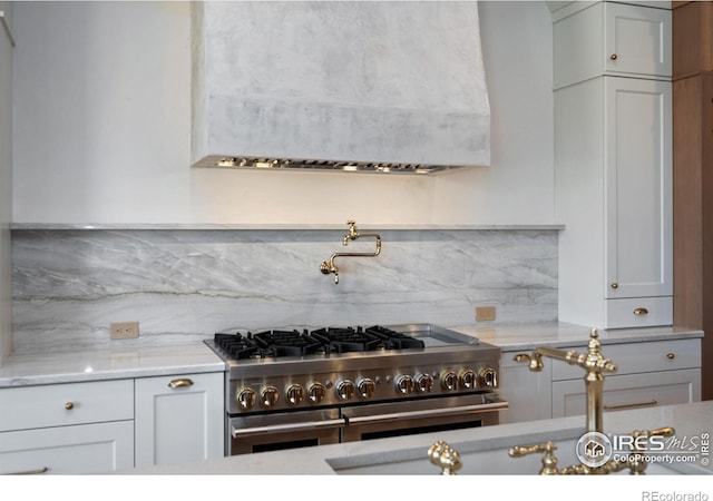 kitchen with decorative backsplash, high end stainless steel range oven, and light stone countertops