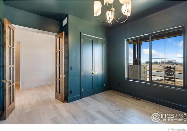 unfurnished bedroom featuring an inviting chandelier, light hardwood / wood-style flooring, and a closet