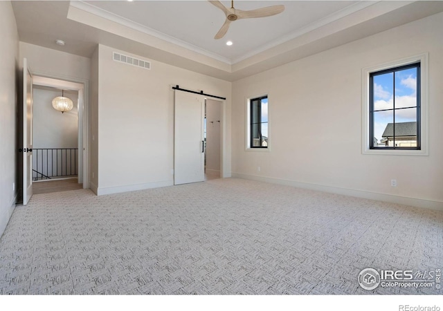 unfurnished bedroom featuring a raised ceiling, a barn door, light colored carpet, and ceiling fan with notable chandelier