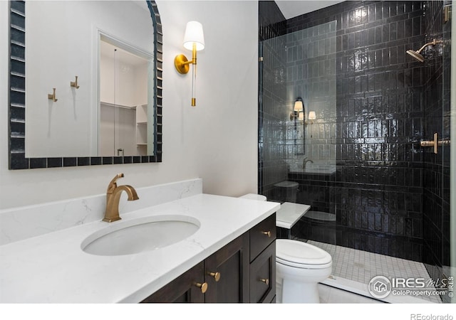 bathroom with tile patterned floors, vanity, toilet, and a tile shower