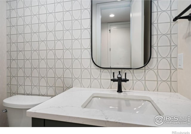 bathroom featuring vanity, toilet, and tile walls