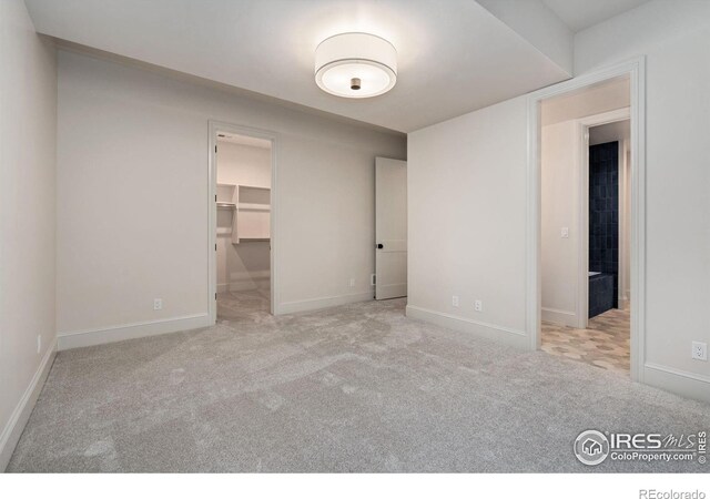 unfurnished bedroom with light colored carpet, a walk in closet, and a closet