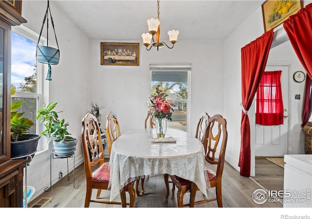 dining space featuring a notable chandelier, a textured ceiling, and hardwood / wood-style flooring