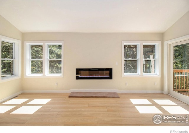 unfurnished living room with light hardwood / wood-style flooring, a healthy amount of sunlight, and vaulted ceiling