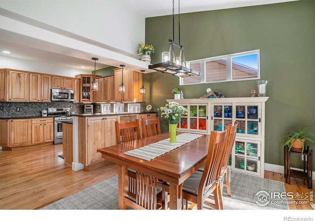 dining space featuring light hardwood / wood-style flooring and a high ceiling