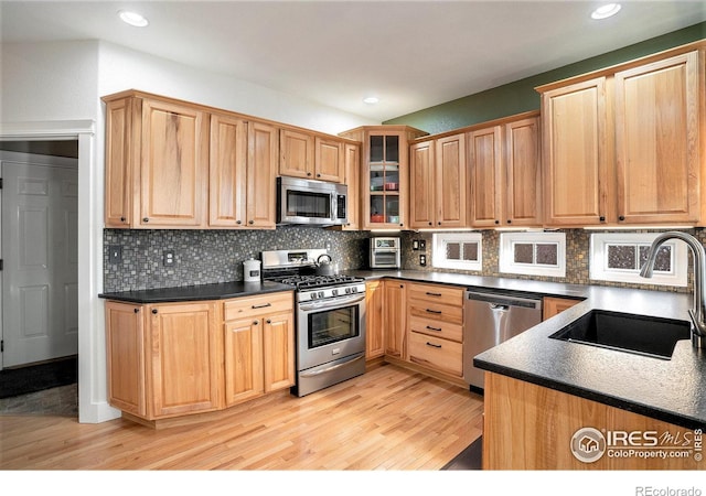 kitchen featuring appliances with stainless steel finishes, light hardwood / wood-style flooring, tasteful backsplash, and sink