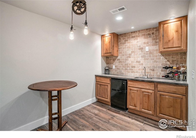 kitchen featuring dark wood-type flooring, decorative backsplash, decorative light fixtures, and black refrigerator