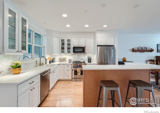 kitchen featuring white cabinets, premium appliances, a breakfast bar area, and sink