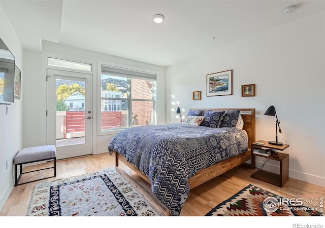 bedroom with access to outside and hardwood / wood-style flooring