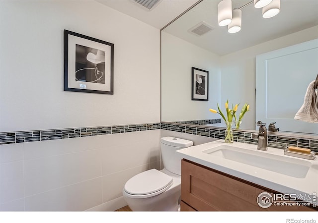 bathroom with vanity, tile walls, and toilet