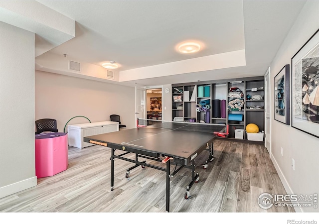 rec room featuring a tray ceiling and light hardwood / wood-style flooring