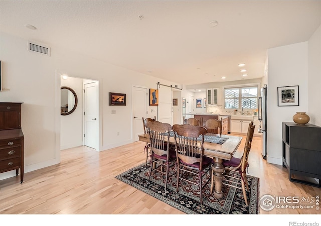 dining space featuring a barn door, sink, and light hardwood / wood-style flooring