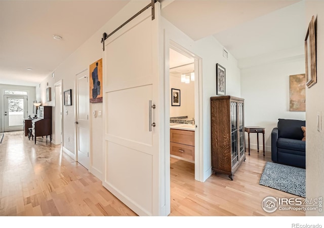 corridor with a barn door and hardwood / wood-style flooring