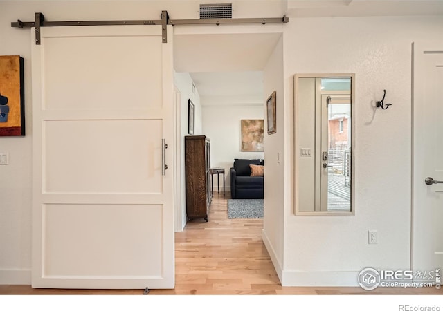 hallway featuring a barn door and light wood-type flooring