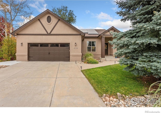 view of front of house with solar panels, a front yard, and a garage