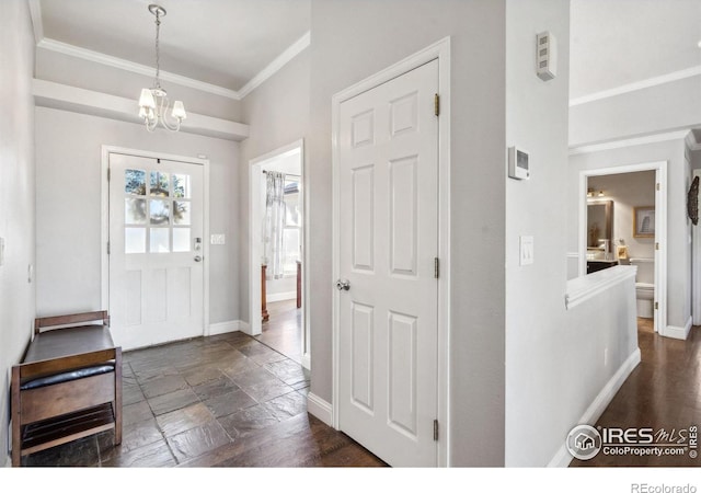 foyer entrance featuring crown molding and an inviting chandelier