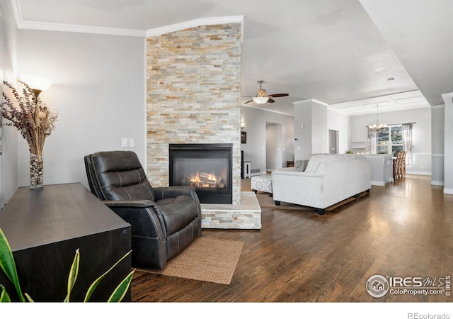 living room featuring crown molding, a stone fireplace, dark hardwood / wood-style flooring, and ceiling fan with notable chandelier