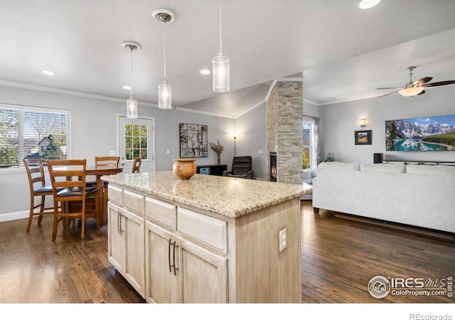 kitchen featuring a kitchen island, dark wood-type flooring, hanging light fixtures, ornamental molding, and ceiling fan