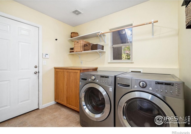 washroom featuring washer and clothes dryer, light tile patterned flooring, and cabinets