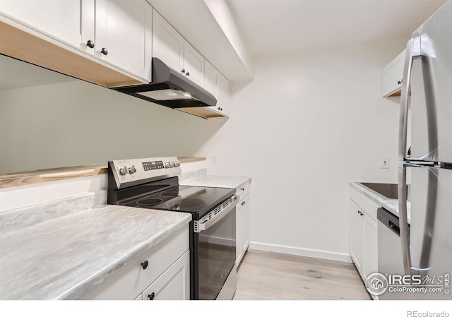 kitchen with appliances with stainless steel finishes, white cabinets, and light hardwood / wood-style floors