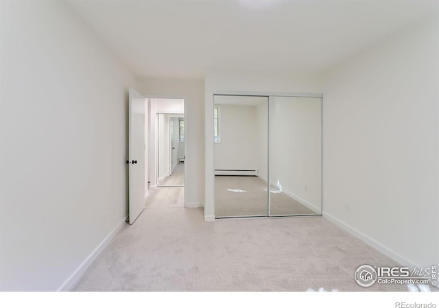 unfurnished bedroom featuring a closet, light carpet, and a baseboard heating unit