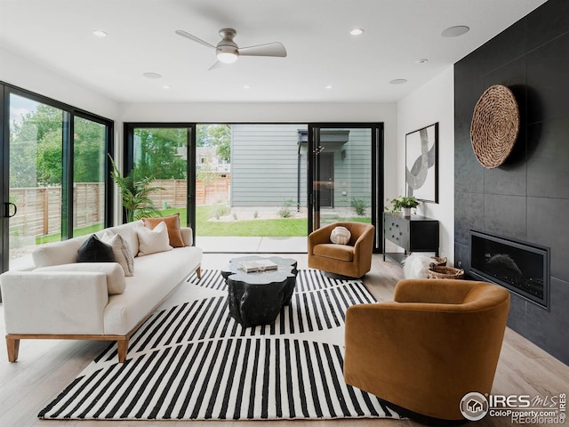 living room with light hardwood / wood-style flooring, a fireplace, and ceiling fan