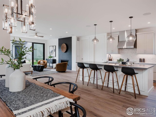 dining room with light hardwood / wood-style flooring, sink, a tile fireplace, and ceiling fan