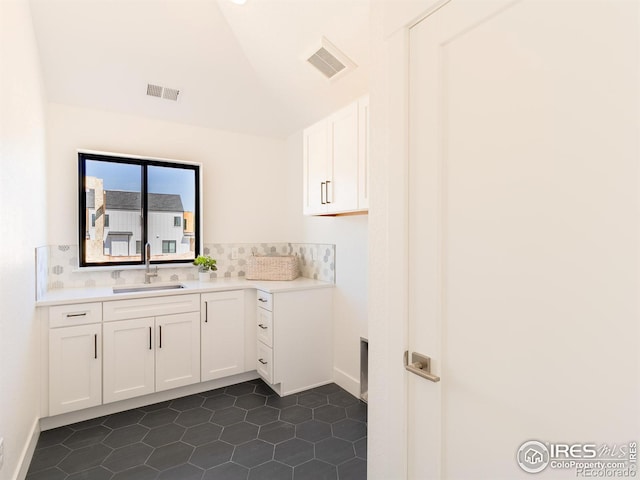 interior space featuring lofted ceiling, sink, dark tile patterned floors, and white cabinets