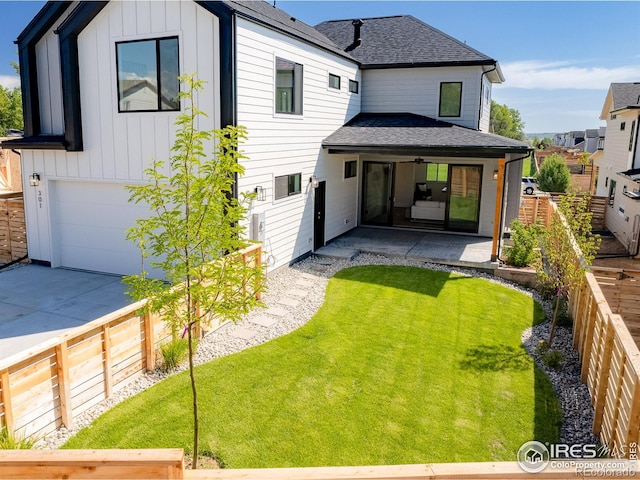 back of house featuring a lawn and a garage