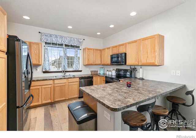 kitchen featuring black appliances, sink, kitchen peninsula, and a kitchen breakfast bar