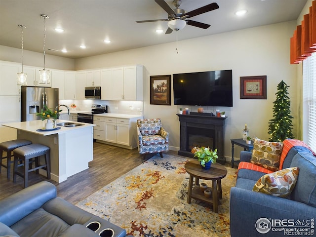 living room with dark wood-type flooring, ceiling fan, and sink