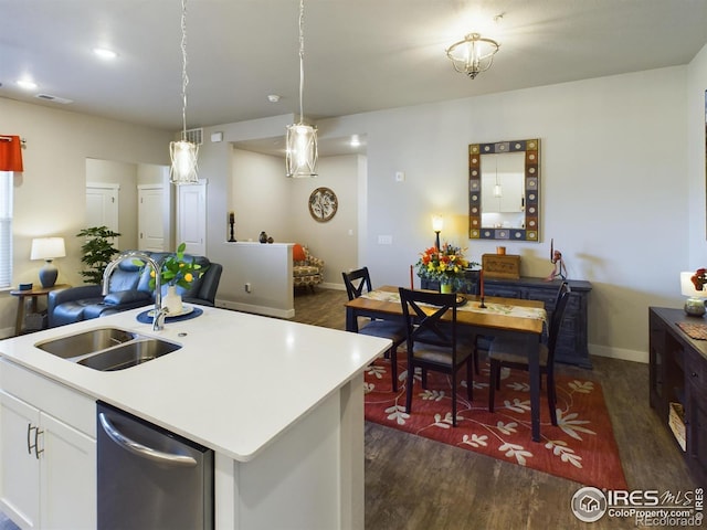 kitchen featuring dark hardwood / wood-style floors, a center island with sink, pendant lighting, stainless steel dishwasher, and white cabinets