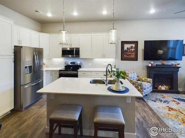 kitchen with a kitchen island with sink, dark wood-type flooring, white cabinets, and stainless steel appliances