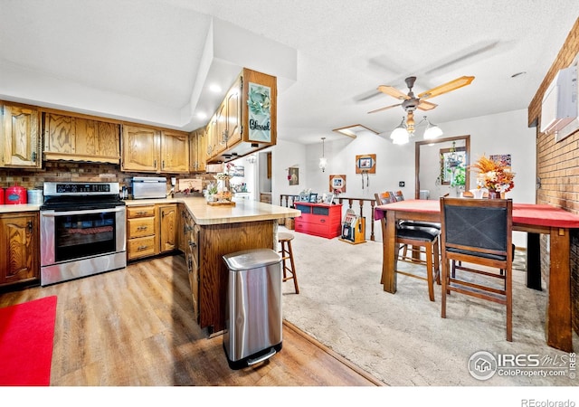 kitchen with light carpet, tasteful backsplash, a textured ceiling, stainless steel stove, and a center island