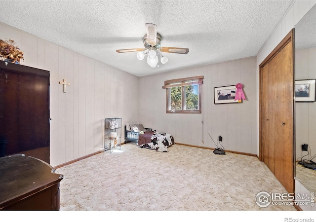 interior space with wooden walls, a textured ceiling, and ceiling fan