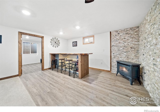 bar with blue cabinets, light wood-type flooring, and a wood stove