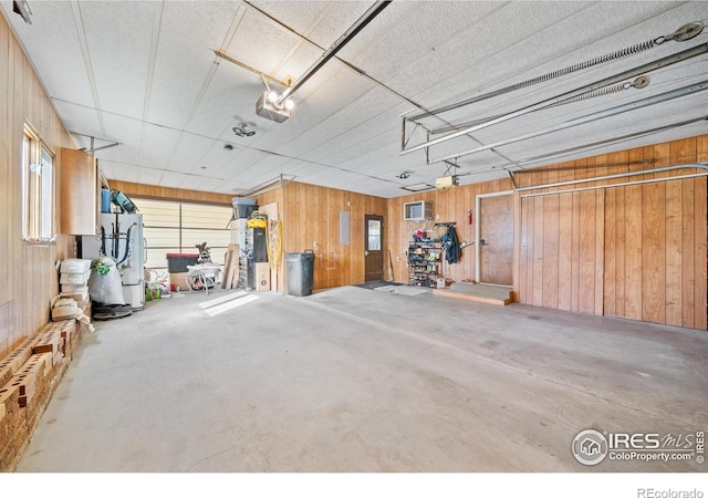 garage featuring a garage door opener, a wall unit AC, fridge, and wood walls