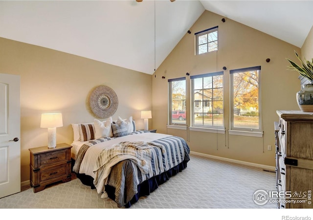 bedroom with light colored carpet and high vaulted ceiling