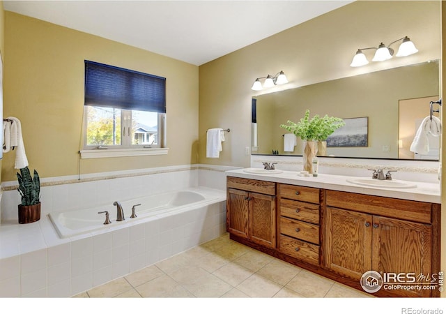 bathroom featuring tiled tub, vanity, and tile patterned flooring