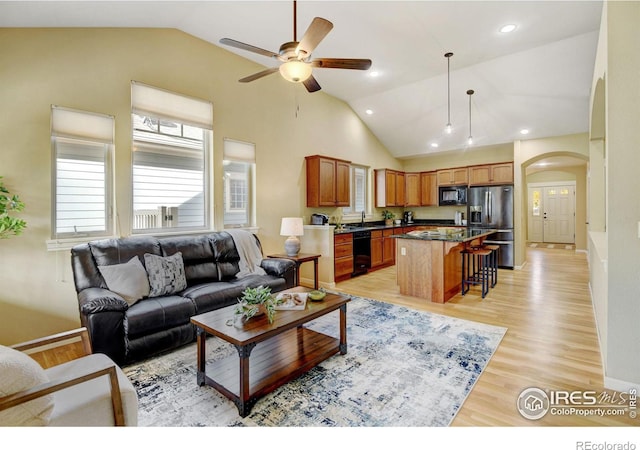 living room with ceiling fan, high vaulted ceiling, sink, and light hardwood / wood-style floors