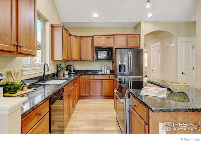 kitchen with dark stone counters, a center island, sink, and black appliances