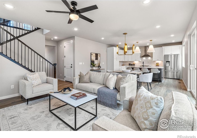 living room with sink, light hardwood / wood-style flooring, and ceiling fan with notable chandelier